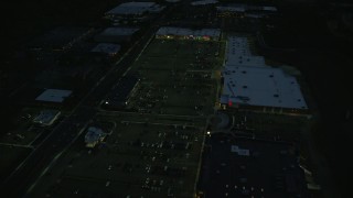 AX146_163E - 6k aerial stock footage approaching an office building and tilt to strip mall, Westwood, Massachusetts, night