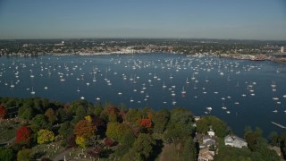 AX147_033E - 6K aerial stock footage flying over harbor with boats toward coastal community and warehouses, Salem, Massachusetts