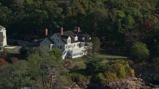AX147_055 - 6K aerial stock footage approaching an oceanfront mansion among trees, autumn, Beverly, Massachusetts