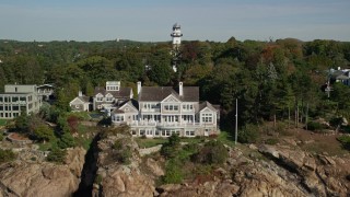 AX147_064E - 6K aerial stock footage revealing oceanfront homes and lighthouse among trees, Manchester-by-the-Sea, Massachusetts