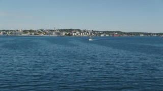 AX147_085 - 6k aerial stock footage flying low over harbor, approaching coastal town, Gloucester, Massachusetts