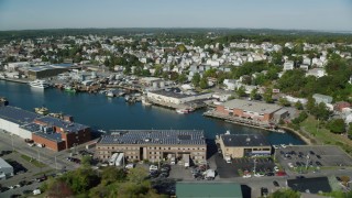 AX147_090 - 6k aerial stock footage flying by coastal town, warehouses, Gloucester, Massachusetts