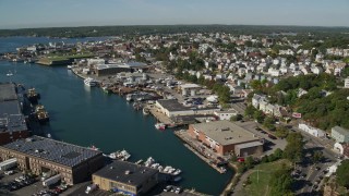 AX147_090E - 6K aerial stock footage flying by coastal town, warehouses, Gloucester, Massachusetts