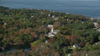 AX147_131E - 6K aerial stock footage flying over trees, pond and church in small coastal town, autumn, Gloucester, Massachusetts