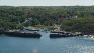 AX147_134 - 6k aerial stock footage flying away from small coastal town among autumn trees, Gloucester, Massachusetts