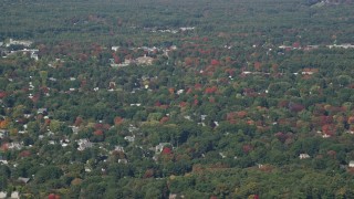 AX147_157 - 6K aerial stock footage flying over houses among colorful autumn trees, Hampton, New Hampshire