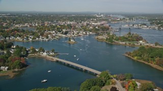 AX147_173 - 6K aerial stock footage flying over a small bridge toward a coastal town in autumn, Portsmouth, New Hampshire