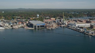 AX147_174 - 6K aerial stock footage flying by a naval shipyard in autumn, Kittery, Maine