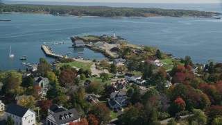 AX147_191E - 6K aerial stock footage flying over coastal community in autumn toward a lighthouse, New Castle, New Hampshire