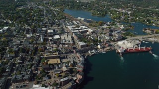 AX147_203 - 6k aerial stock footage flying by coastal town and a cargo ship in autumn, Portsmouth, New Hampshire