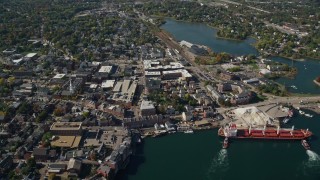 AX147_203E - 6K aerial stock footage flying by coastal town and a cargo ship in autumn, Portsmouth, New Hampshire