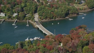 AX147_226 - 6K aerial stock footage flying by small bridge, colorful trees, Kittery, Maine