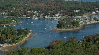 AX147_231 - 6k aerial stock footage approaching coastal town, tilt up to colorful forest, autumn, York, Maine