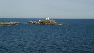 AX147_236 - 5.5K aerial stock footage flying low over the ocean, approaching Cape Neddick Light, York, Maine