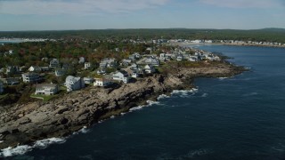 AX147_244 - 6k aerial stock footage flying by coastal town, rocky shore, autumn, York, Maine