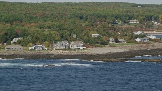AX147_245 - 6k aerial stock footage flying by oceanfront homes, colorful dense forest, autumn, York, Maine