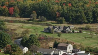 AX147_290 - 6K aerial stock footage flying by riverfront rural homes, colorful forest, Biddeford, Maine