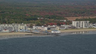 AX147_295 - 6K aerial stock footage flying by beach and pier, colorful autumn trees, Old Orchard Beach, Maine