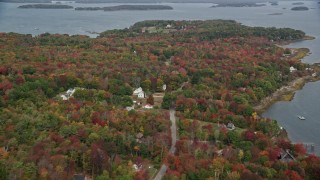 AX147_371 - 6K aerial stock footage flying by rural homes on an island with colorful forest, Chebeague Island, Maine