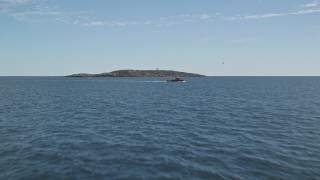 AX147_386E - 6K aerial stock footage flying low over the ocean approaching boat and Seguin Island, Phippsburg, Maine