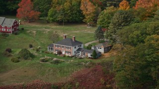 AX147_407 - 6K aerial stock footage flying by an isolated waterfront home, colorful autumn trees, Phippsburg, Maine