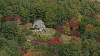 AX147_409 - 6k aerial stock footage flying by an isolated rural home, colorful trees in autumn, Arrowsic, Maine