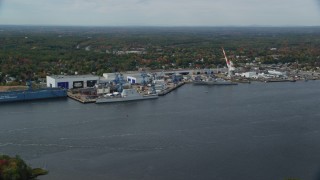 AX147_412 - 6k aerial stock footage flying by waterfront General Dynamics Bath Iron Works, autumn, Bath, Maine