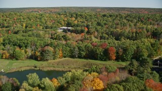 AX148_008 - 6K aerial stock footage flying over colorful forest, approach small warehouse, autumn, Newcastle, Maine