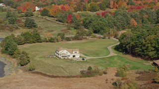 AX148_010E - 6K aerial stock footage flying by an isolated rural home, colorful forest, autumn, Newcastle, Maine