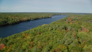 AX148_023 - 6k aerial stock footage flying by a colorful forest, Biscay Pond, autumn, Damariscotta, Maine