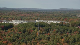 AX148_061 - 6k aerial stock footage flying by Maine State Prison, colorful forest, autumn, Warren, Maine