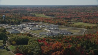 AX148_062E - 6K aerial stock footage orbiting Maine State Prison, colorful forest, autumn, Warren, Maine