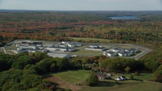 AX148_063 - 6k aerial stock footage orbiting Maine State Prison, colorful forest, autumn, Warren, Maine