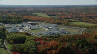 AX148_064 - 6k aerial stock footage orbiting Maine State Prison, colorful forest, autumn, Warren, Maine