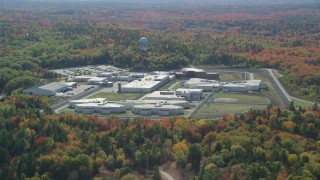 AX148_065 - 6k aerial stock footage orbiting Maine State Prison, colorful forest, autumn, Warren, Maine