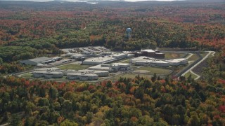 AX148_065E - 6K aerial stock footage orbiting Maine State Prison, colorful forest, autumn, Warren, Maine