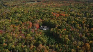 AX148_079 - 6K aerial stock footage flying by a lone rural home, colorful forest, autumn, Owls Head, Maine