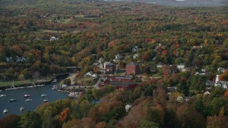 AX148_101E - 6K aerial stock footage orbiting a small coastal town and harbor in autumn, Rockport, Maine