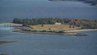 AX148_131 - 6K aerial stock footage flying by an isolated island home, trees in autumn, Hog Island, Maine