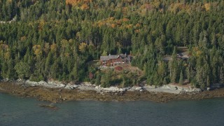 AX148_136 - 6K aerial stock footage flying by a waterfront island home in autumn, Little Deer Isle, Maine