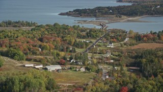 AX148_138 - 6K aerial stock footage flying by island homes, Little Deer Isle Road, autumn, Little Deer Isle, Maine