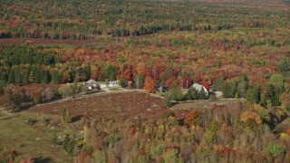 AX148_146E - 6K aerial stock footage flying by rural homes and colorful forest, autumn, Sedgwick, Maine