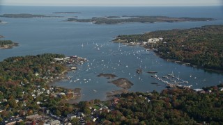 AX148_159E - 6K aerial stock footage flying over trees in autumn, approaching the Southwest Harbor, Maine
