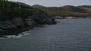 AX148_177E - 5.5K aerial stock footage flying by forested, rocky coastline, autumn, Seal Harbor, Mount Desert Island, Maine