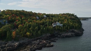 AX148_188E - 5.5K aerial stock footage flying by forested coastline, reveal waterfront mansion, Bar Harbor, Maine