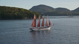 AX148_198 - 5.5K stock footage aerial video sailing ship and partial fall foliage, Bar Harbor, Maine