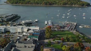 AX148_208 - 5.5K stock footage aerial video approaching harbor with boats from coastal town, autumn, Bar Harbor, Maine
