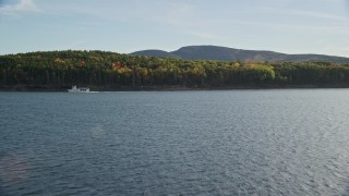 AX148_209E - 5.5K aerial stock footage flying over water toward ferry and island with fall foliage, Bar Harbor, Maine