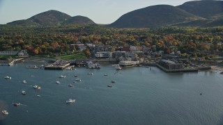 AX148_211E - 5.5K aerial stock footage flying over color changing trees toward harbor and coastal town, autumn, Bar Harbor, Maine