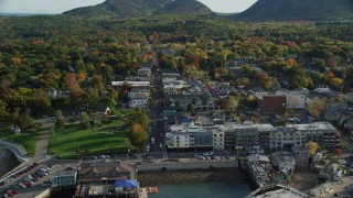 AX148_213 - 5.5K stock footage aerial video flying over docked ferries toward Main Street in coastal town with fall foliage, Bar Harbor, Maine